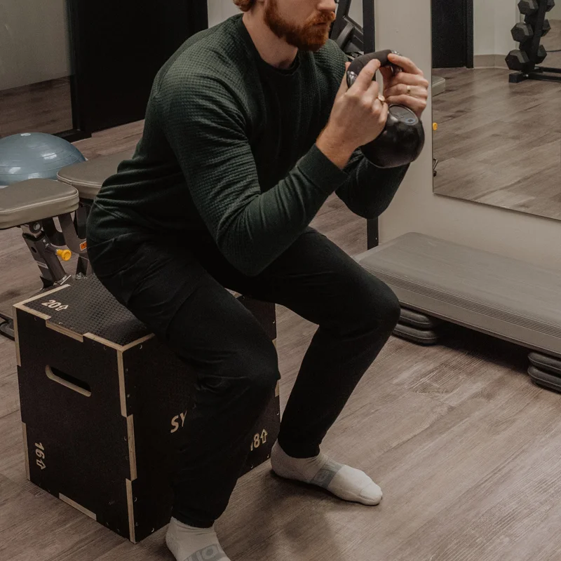 Patient performing goblet squat on plyo box during progressive post-surgical rehabilitation at Pro Motion Clinic Kelowna