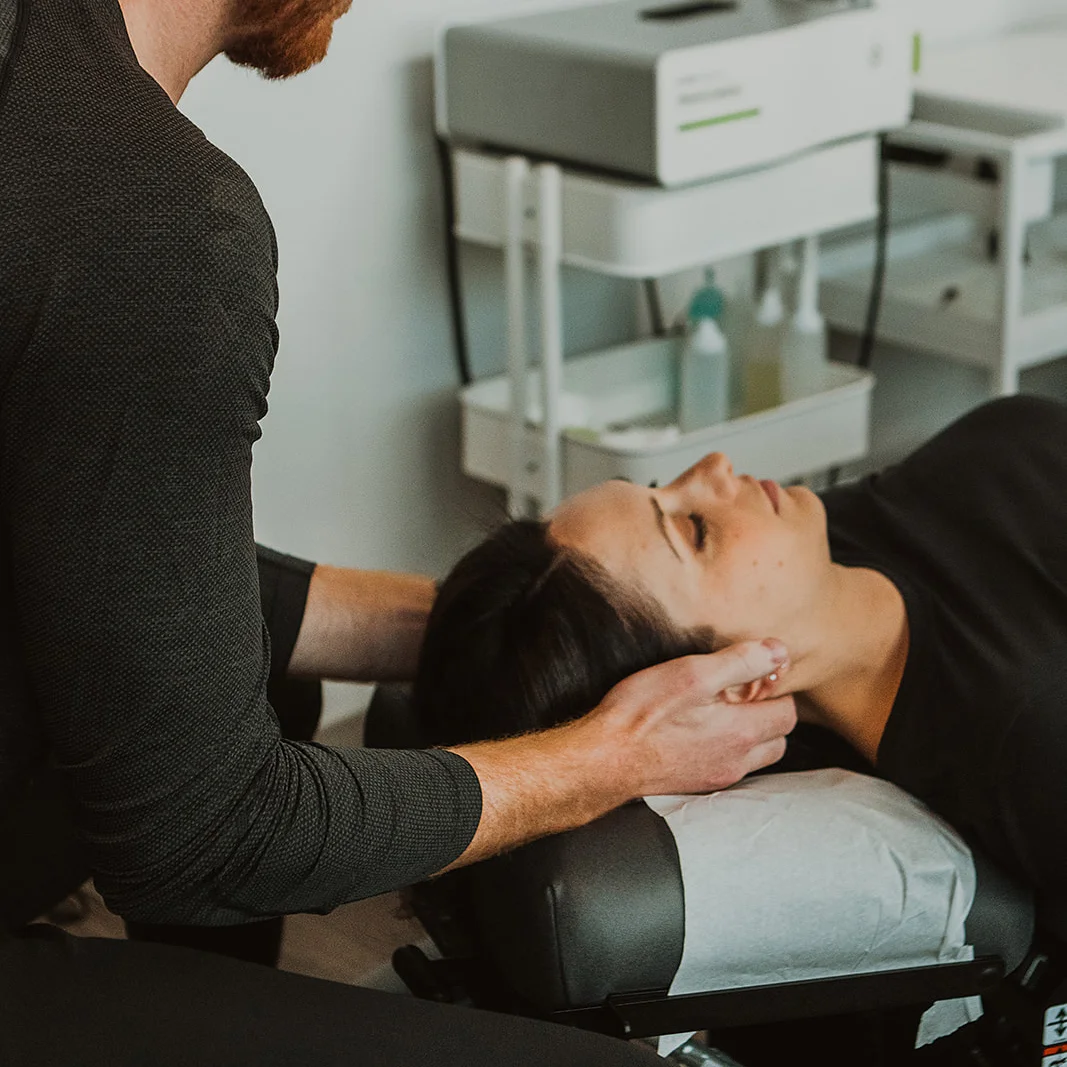 Physiotherapist performing cervical manual therapy on patient lying down for TMJ jaw pain treatment in Kelowna
