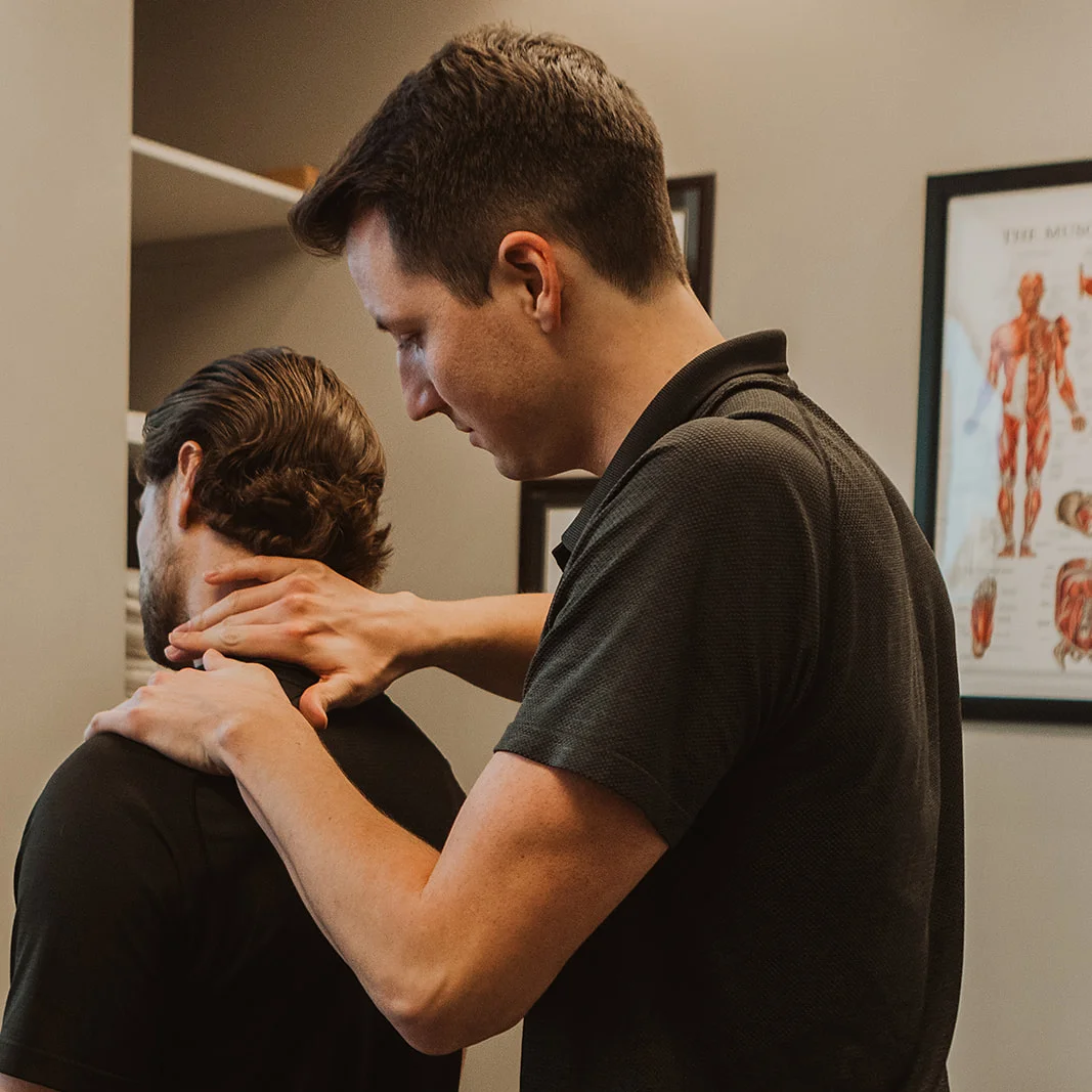 Physiotherapist assessing patient's cervical spine and neck for TMJ disorder and jaw pain in Kelowna