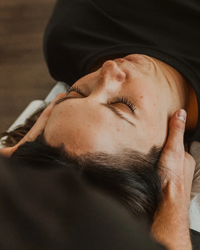 Registered massage therapist applying gentle cranial and cervical therapy for concussion treatment in Kelowna