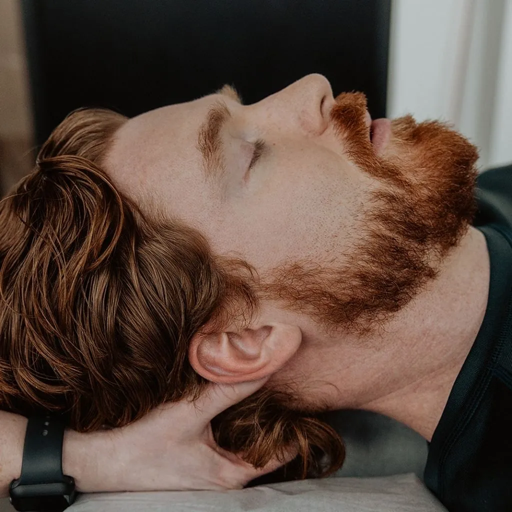 Massage therapist supporting patient's neck and base of skull during headache and migraine therapy in Kelowna