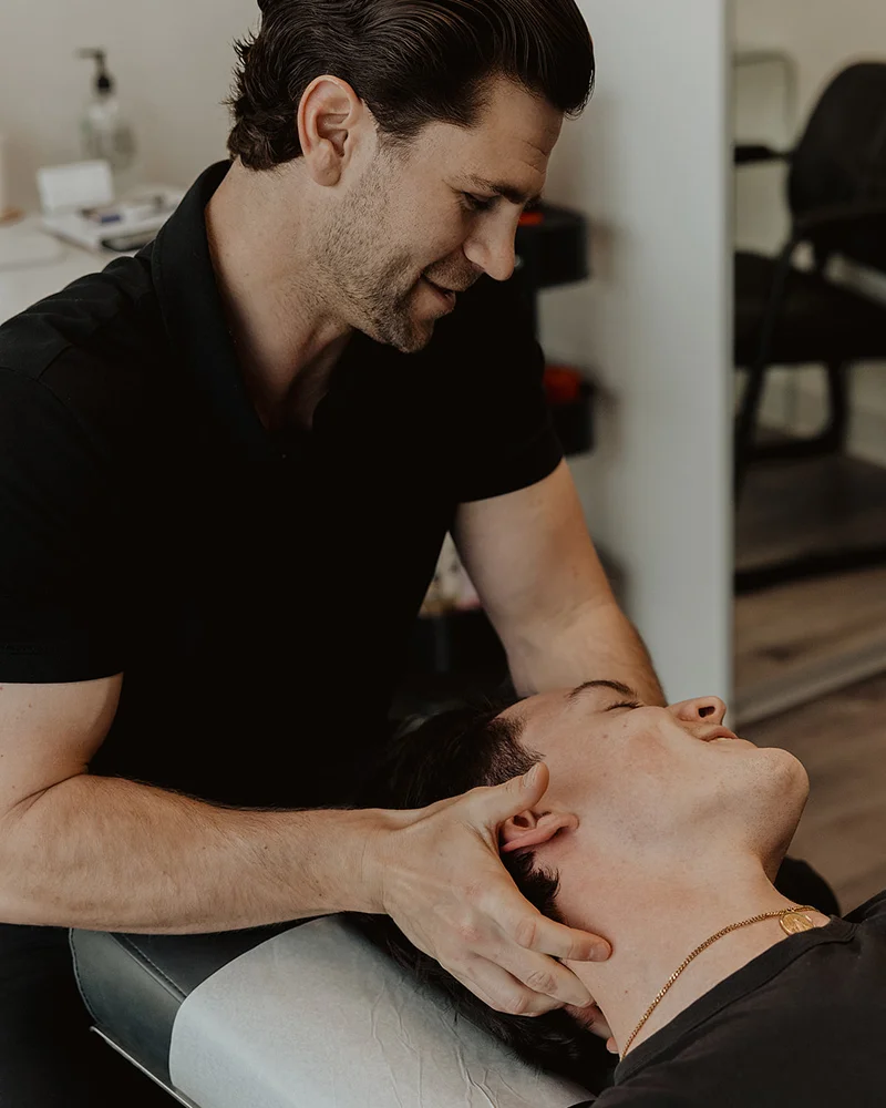 Registered massage therapist performing cervical manual therapy on patient for concussion recovery in Kelowna