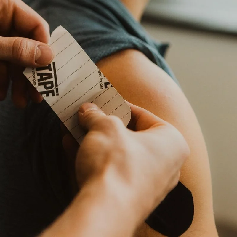Physiotherapist peeling RockTape kinesiology tape backing before applying to patient's arm in Kelowna clinic