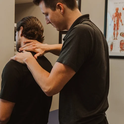 Physiotherapist assessing neck and upper back pain during treatment session in Kelowna