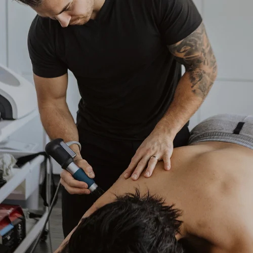 Shockwave therapy applied to upper back muscles for pain management and recovery