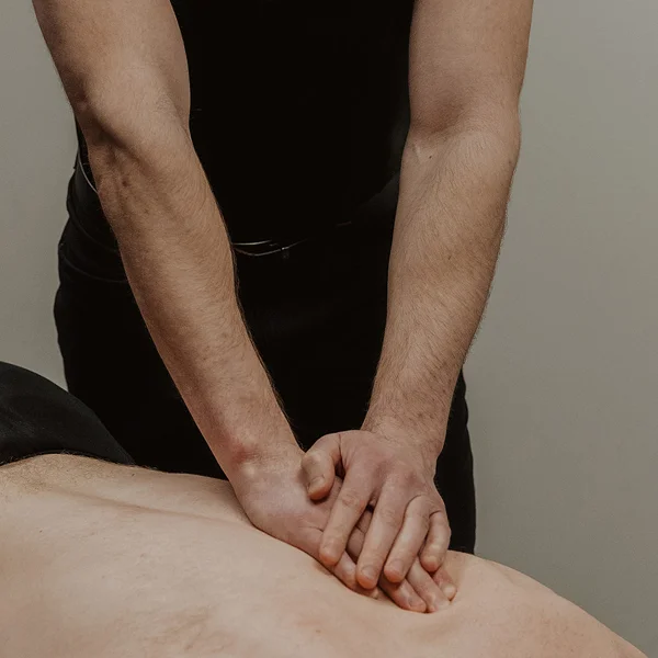 Registered massage therapist applying deep pressure to relieve back muscle tension