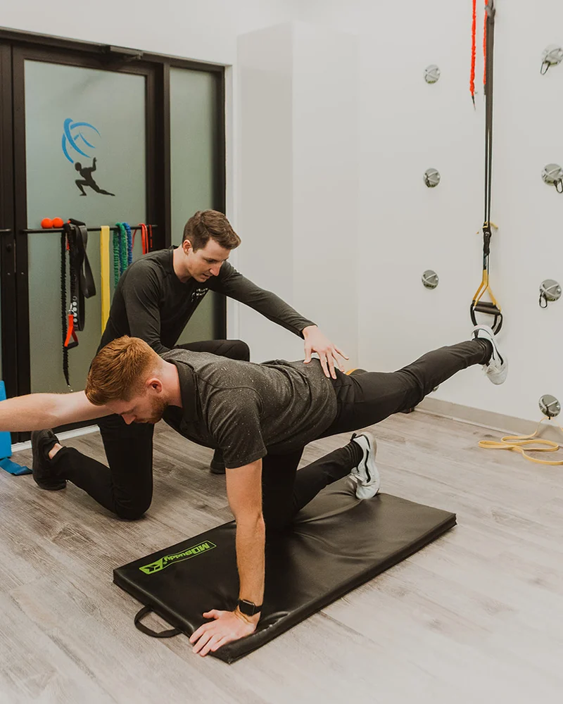 Kinesiologist guiding suspension training exercise to improve core strength at Pro Motion Clinic