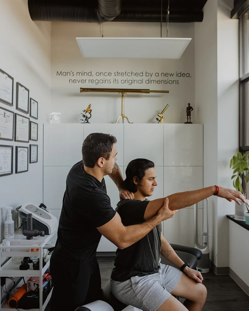 Chiropractor performing shoulder mobility assessment on patient at Pro Motion Clinic Kelowna