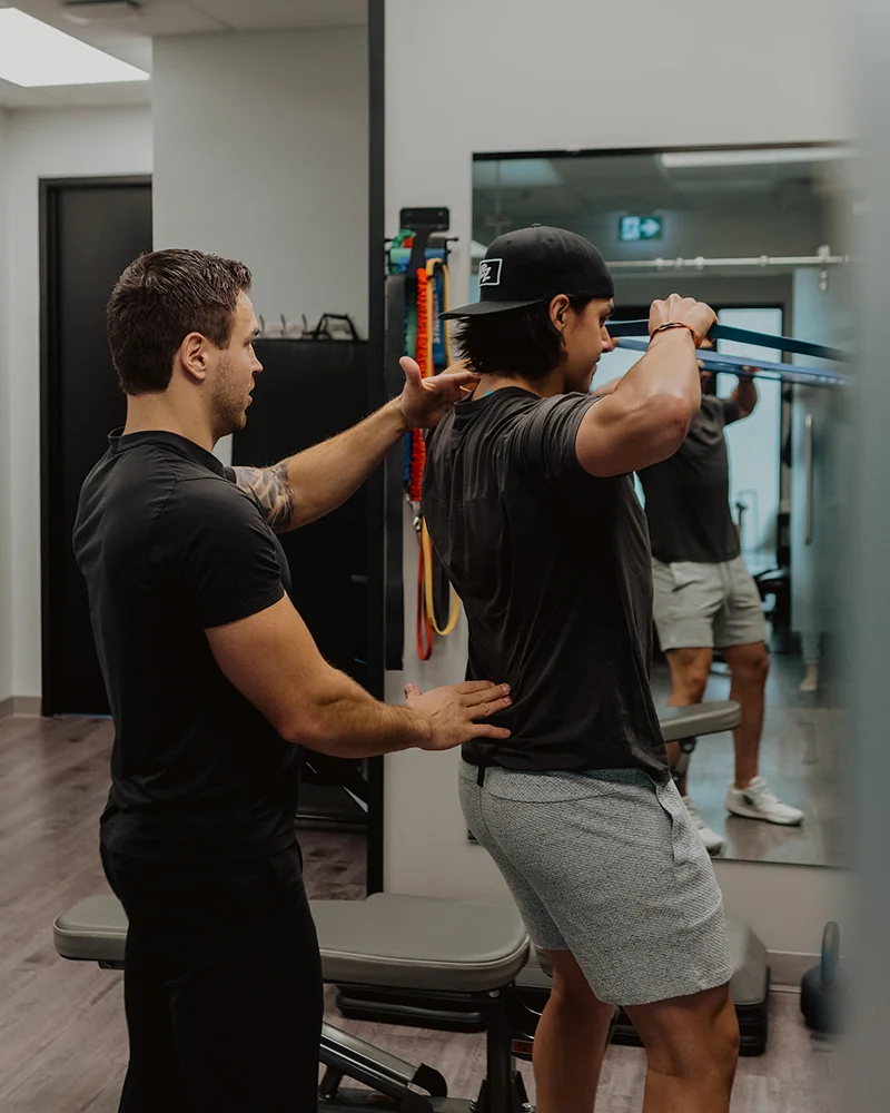 Kinesiologist evaluating posture and back alignment using resistance band during movement screen