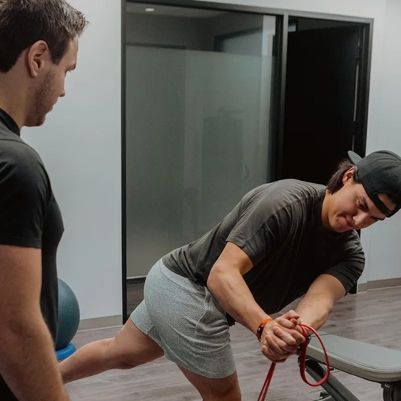 Chiropractor supervising resistance band exercise for mobility and injury recovery in Kelowna