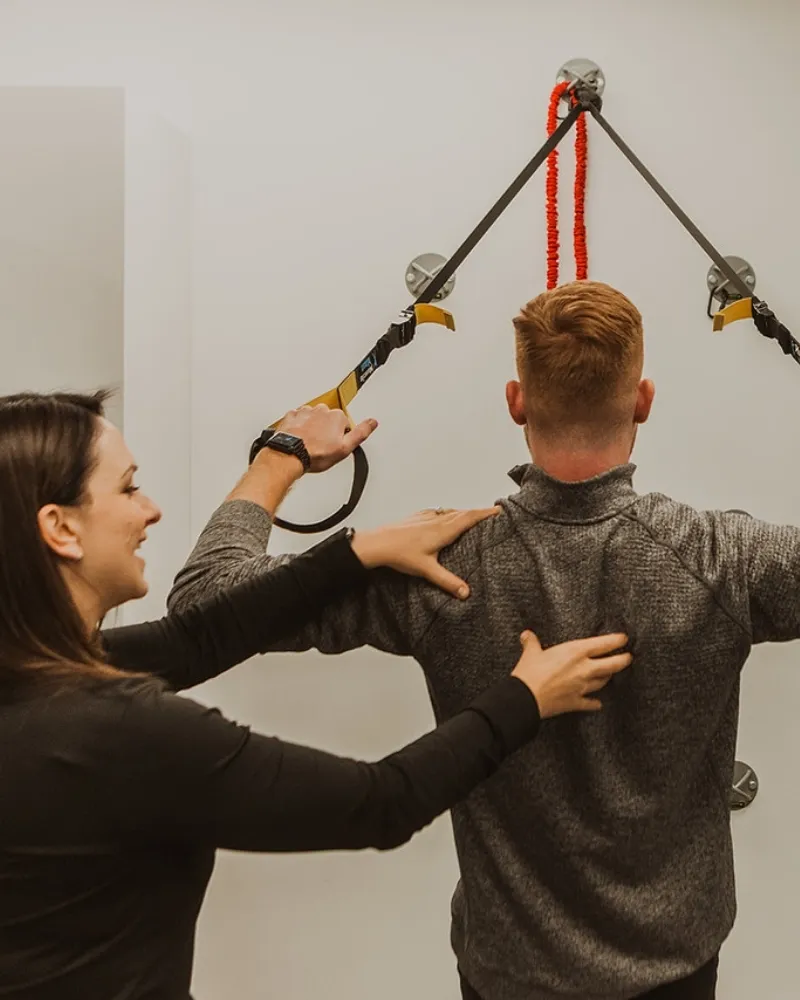 Kinesiologist assisting upper body mobility exercise using straps at Pro Motion Clinic Kelowna