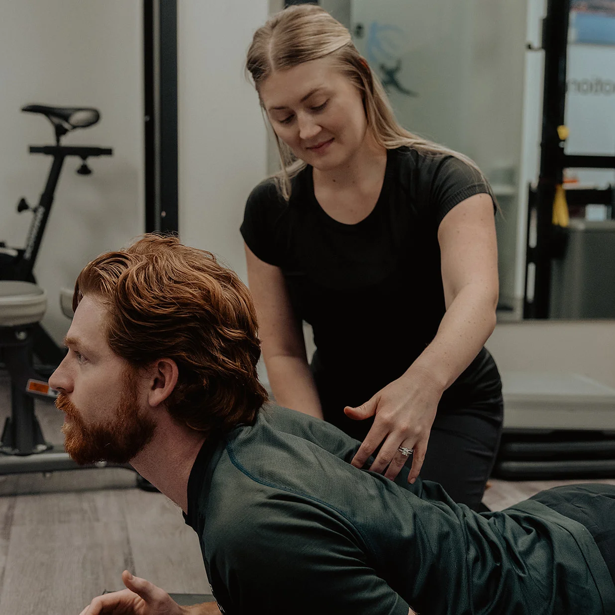 Registered massage therapist guiding patient through clinical Pilates spinal extension exercise in Kelowna