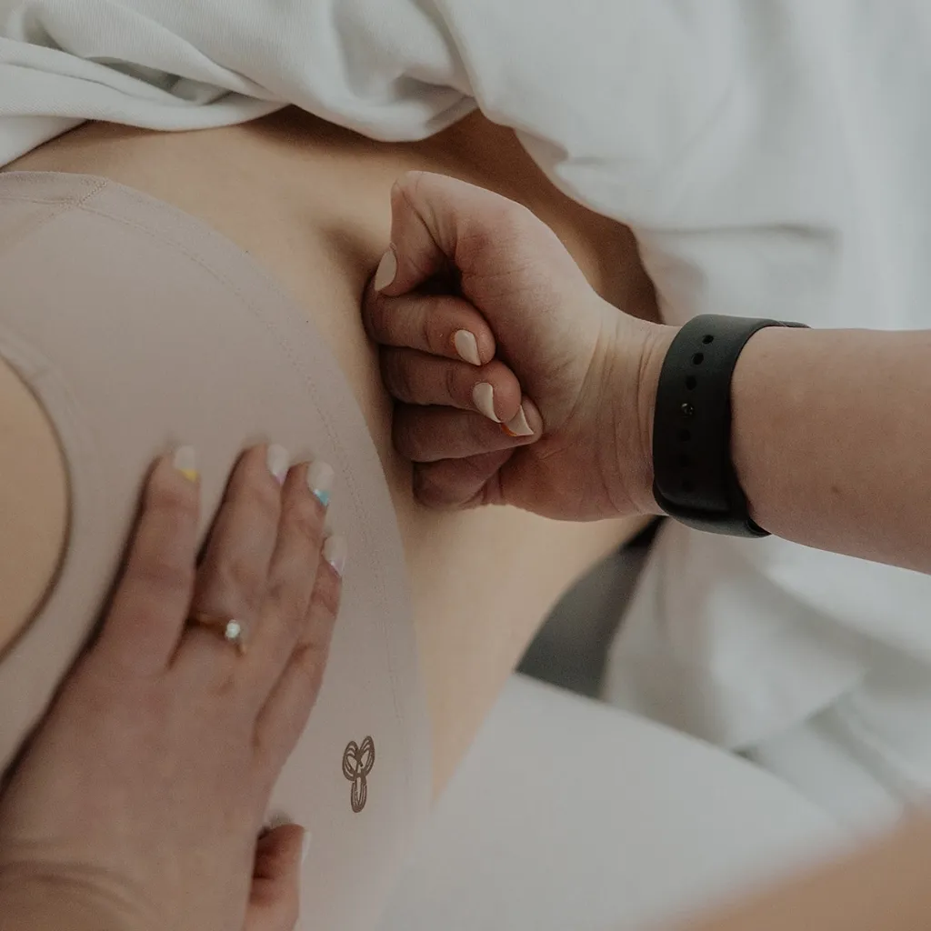 Registered massage therapist applying deep tissue knuckle pressure to patient's lower back for pain relief in Kelowna