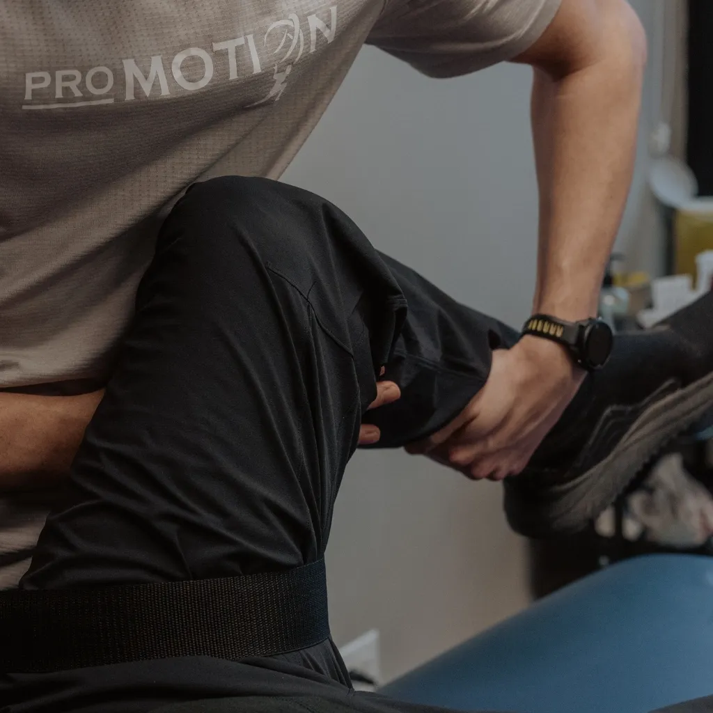 Pro Motion Clinic physiotherapist performing hip joint mobility assessment for osteoarthritis management in Kelowna