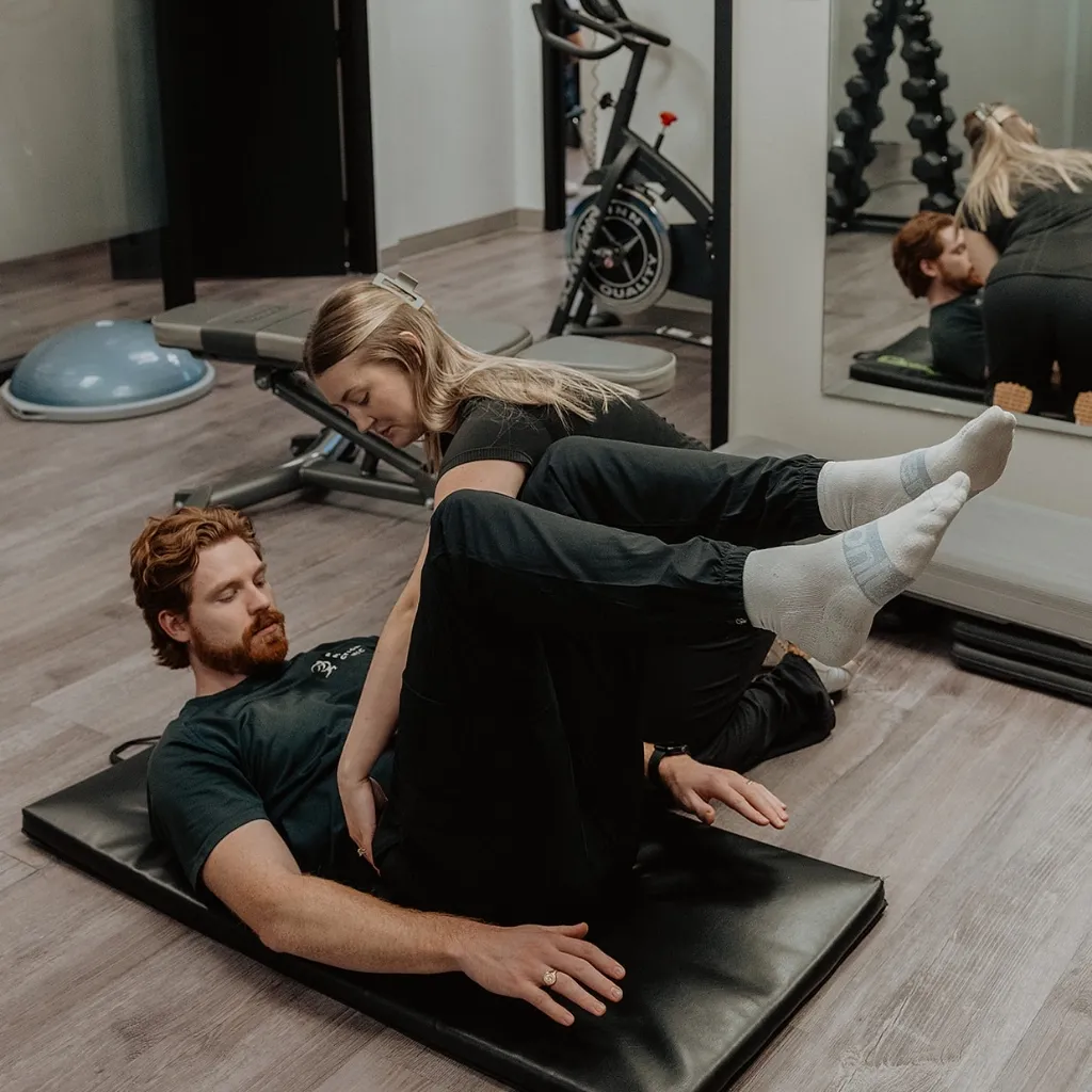 Registered massage therapist guiding patient through leg movement assessment during NeuroKinetic therapy in Kelowna