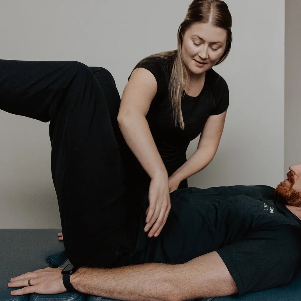 Registered massage therapist testing hip and core muscle activation during NeuroKinetic therapy session in Kelowna
