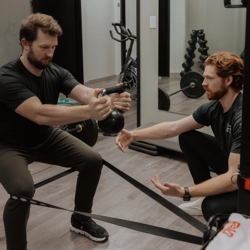 Kinesiologist coaching patient through banded hip hinge exercise for chronic pain and movement rehab in Kelowna