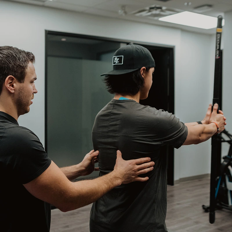 Practitioner guiding patient through overhead mobility screen during TPI assessment at Pro Motion Clinic Kelowna