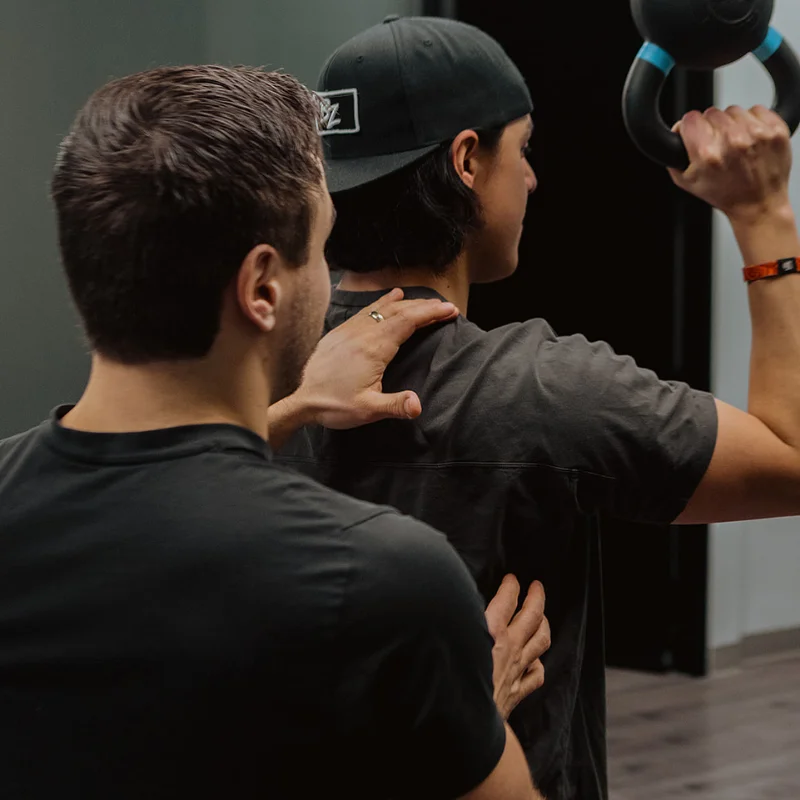 Practitioner cueing shoulder and spinal alignment during kettlebell exercise for chronic pain rehab in Kelowna